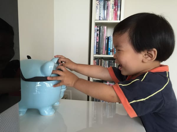 1Y10Ms Putting glasses on his piggy bank